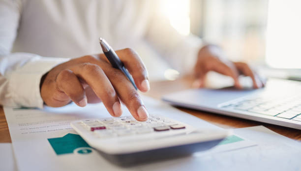 finance, accounting and fintech, a man on a computer and calculator working out his business budget strategy. businessman at his office desk, laptop, money management and financial investment online. - 金融 個照片及圖片檔